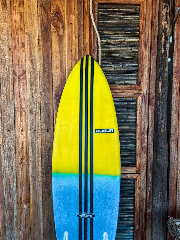 Colorful surfboard leaning on rustic wooden wall, capturing summer vibes.