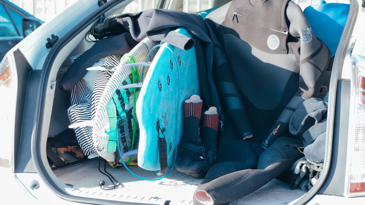 Car trunk loaded with surfboards and wetsuits, ready for beach adventure.